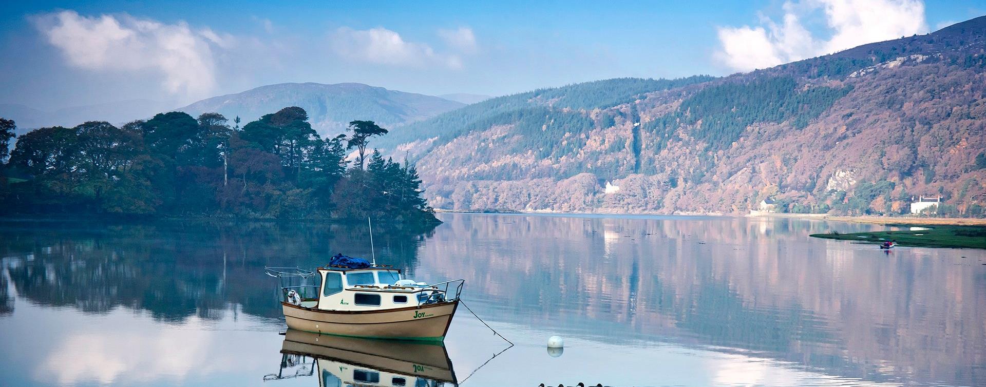 A small boat on the still Mawddach river at Penmaenpool, with autumn woods on the hillside