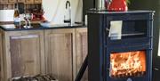 Lit black log burner in front of an oak and slate kitchen unit