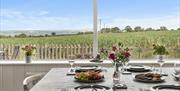 The dining table is set and looks out through the picture windows to the garden and fields beyond