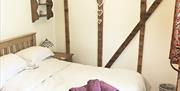 Double bedroom with exposed wood beams and rolled  towels on bed