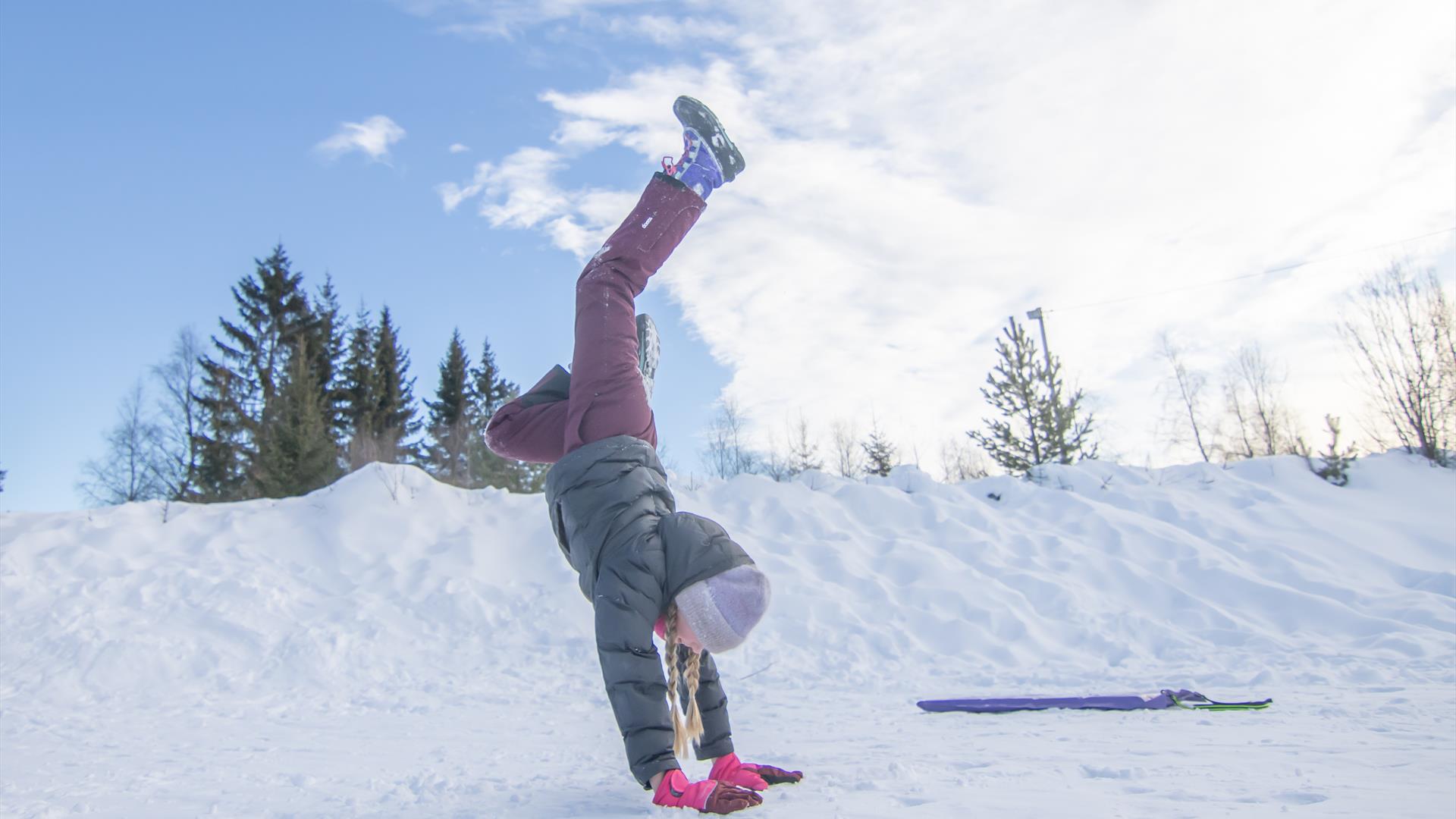 Jente står på henda på Gåsbu vinter