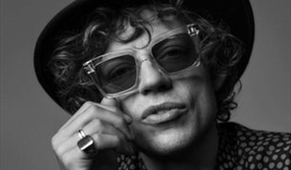 sort hvitt bilde av mann med hatt og briller