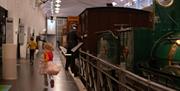 Museumsrom med tog og person som går langs utstillingen. Foto: Kristian Dillerud, Jonas J. Tomter og Ingvild Stubbom