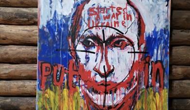Her er ett av maleriene du kan se på utstillingen på Rømma gård. "Murderer", "Started a war in Ukraine" og "Putin" er skrevet over portrettet av presidenten.