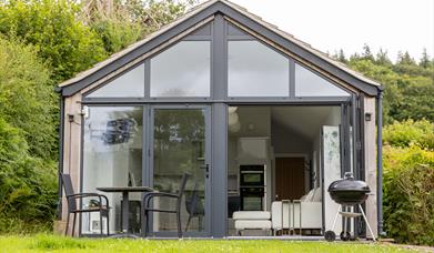 The terrace at the front of the Skirrid, showing off the floor-to-ceiling picture window, barbecue, and table with two chairs