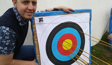 Man_standing_by_target_with_arrow_in_centre