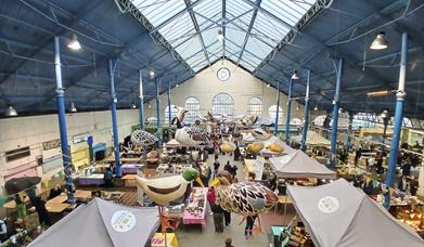 inside Abergavenny Town hall during street food market, art hangs from roof and stalls full of food producers