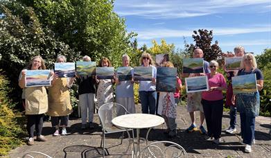 workshop people holding paintings and smiling 