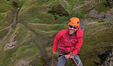 Man abseiling over edge of cliff