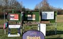 Rogiet Parkrun sign in Rogiet countryside park with runners in background sunny day in monmouthshire