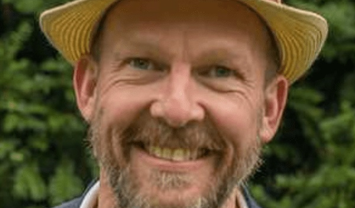 Photo of a smiling man in a straw hat