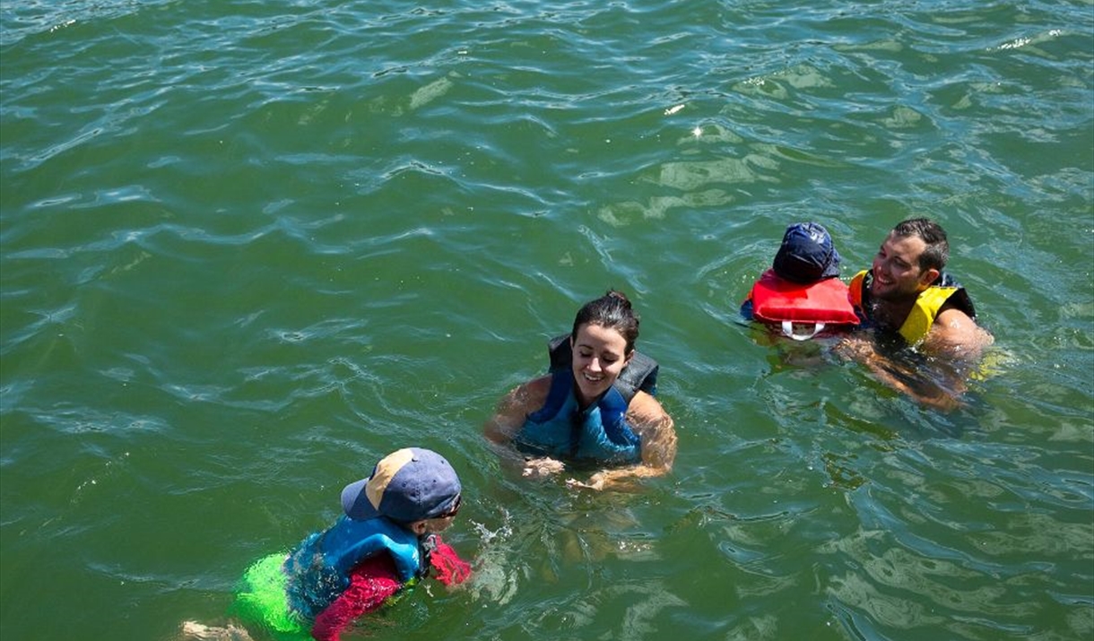 Mother and father with two children playing in the water wearing buoyancies