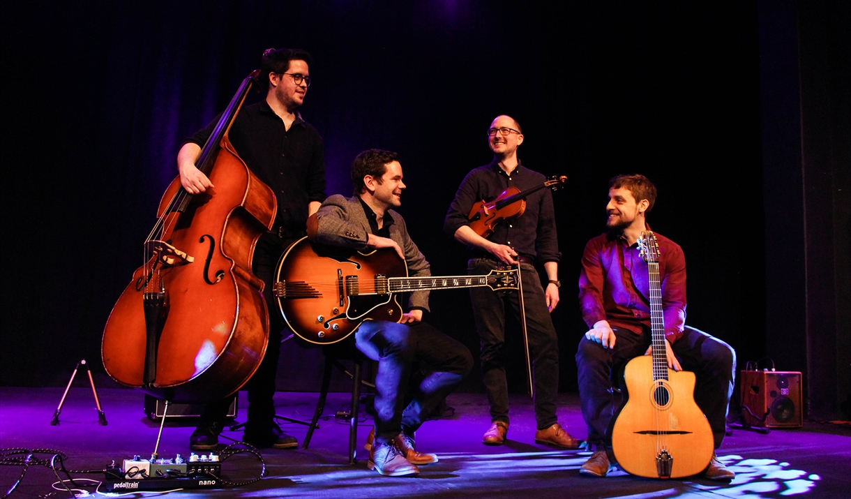 Four members of a band standing on a stage