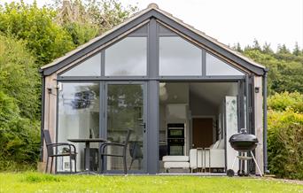 The terrace at the front of the Skirrid, showing off the floor-to-ceiling picture window, barbecue, and table with two chairs