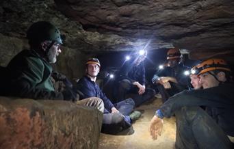 Group of people inside cave with headlamps
