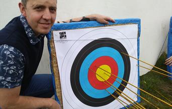 Man_standing_by_target_with_arrow_in_centre