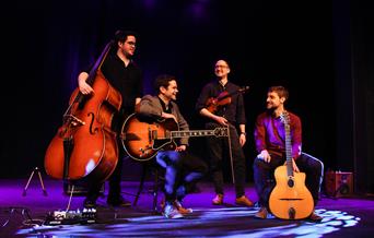 Four members of a band standing on a stage