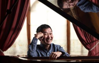 Melvyn Tan sat at piano, smiling.