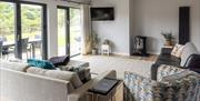 The Sugar Loaf living area looking towards the TV, with two sofas, a small armchair, and French doors.