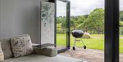 A view out to the terrace from inside the Skirrid, through the open bi-fold doors in the large picture window. There is a folding decorative screen to