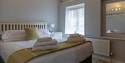 The light and airy Blorenge bedroom with a king size bed, bed side table, and clothes hangers reflected in the mirror.