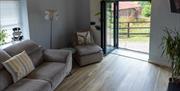 The Blorenge living room with sofa, chair, floor lamp, and juliet balcony with views across the valley.