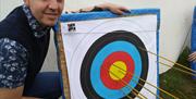 Man_standing_by_target_with_arrow_in_centre