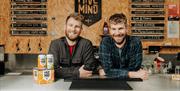 Two owners of the Hive Mind brew co smile whilst leaning on the bar