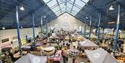inside Abergavenny Town hall during street food market, art hangs from roof and stalls full of food producers