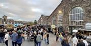 Outside abergavenny town hall during street food market, people enjoy talking to friends and eating food from food stalls
