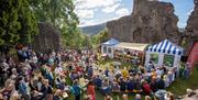 Abergavenny Food Festival in abergavenny castle with crowds watching firepit display on sunny day looks fun