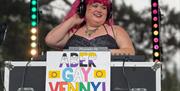 DJ with sign saying "ABER - GAY - VENNY"  at abergavenny pride event