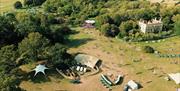Into The Woods Festival UK  ariel shot looking down of field of green grass and woods and festival tents and people