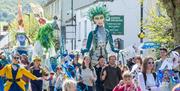 Photograph of people, puppets and flags walking down Monmouth high street during Wye Valley River Festival