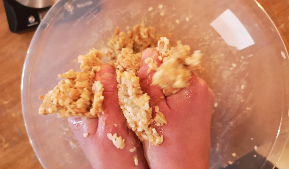 Hands above a bowl squeezing mashed soybeans with koji to make miso Hands above a bowl squeezing mashed soybeans with koji to make miso