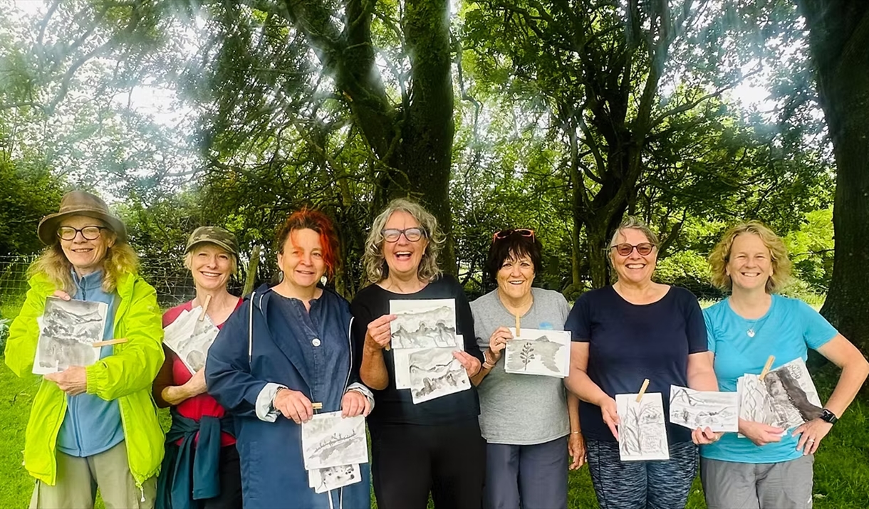 Women holding their artwork under a tree Women holding their artwork under a tree