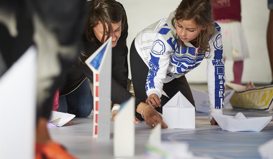 A photograph of two people kneeling down doing a craft activity.