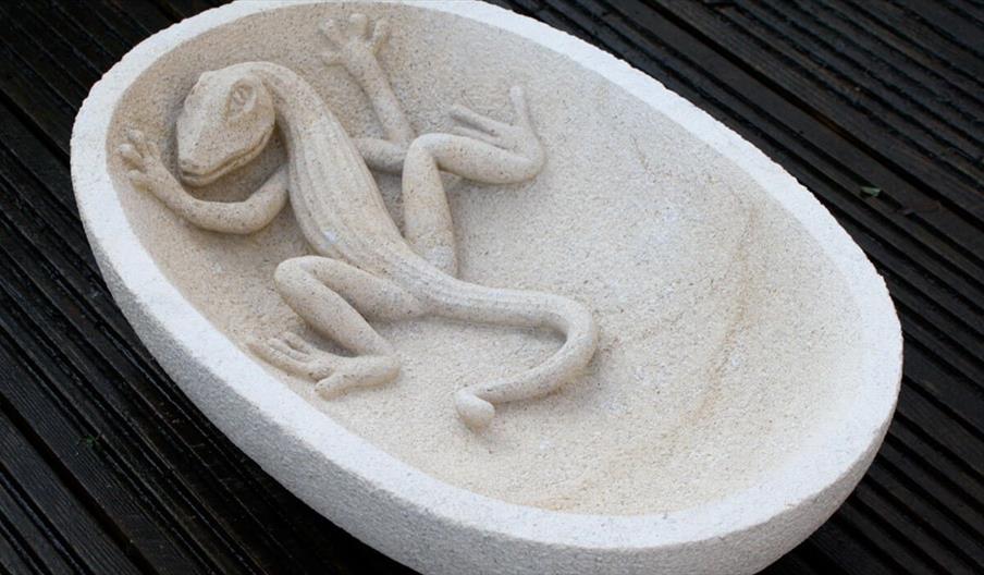 A stone bowl with a reptile carved within the structure