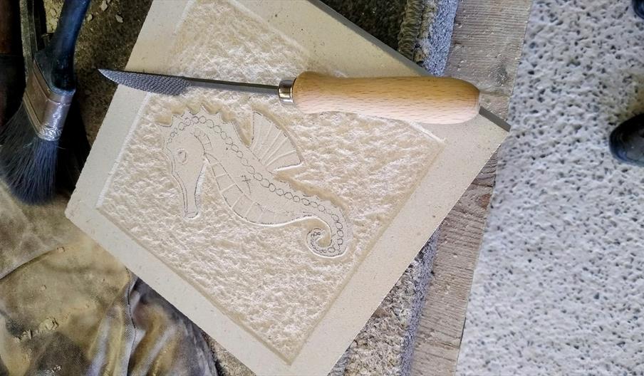 A work in progress image of a slab of stone with a seahorse carved into it