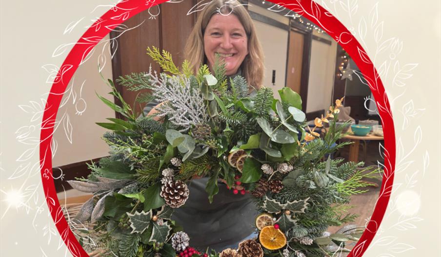A woman holding up a Christmas Wreath