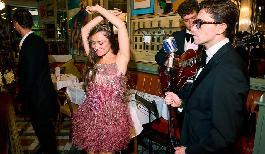 A lady in a pink 1930s style dress dancing to a live performance at The Ivy