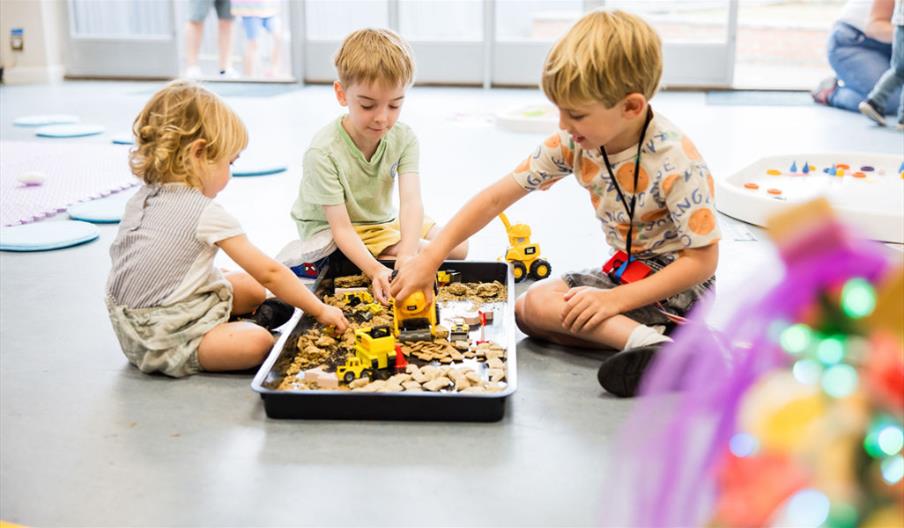 3 pre-school/toddler age children playing in a messy tray