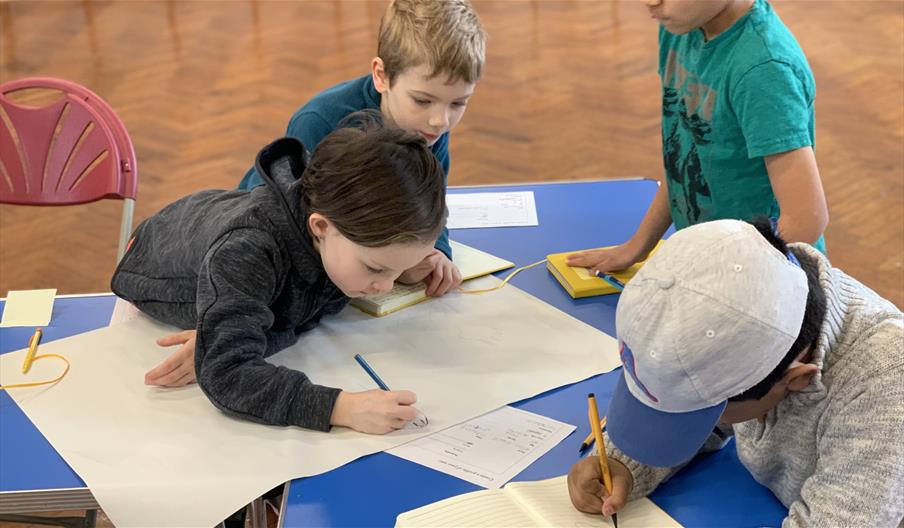 Group of children working on designs round a table.