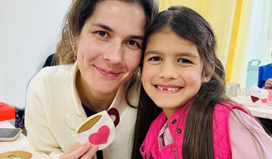 mother and daughter smiling showing a sewn project they have done together
