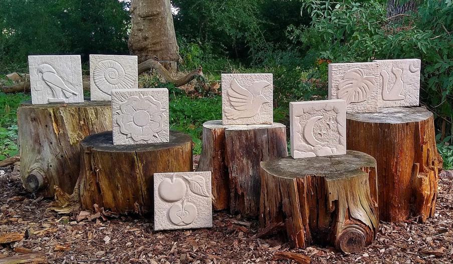 Eight carved stones displayed on tree trunks in a wooded area