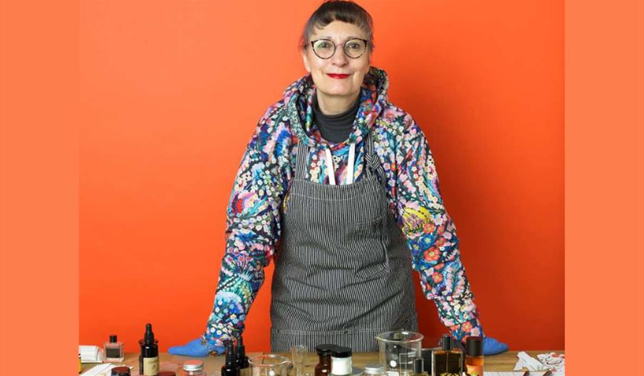 Woman standing at a desk with perfume ingredients.
