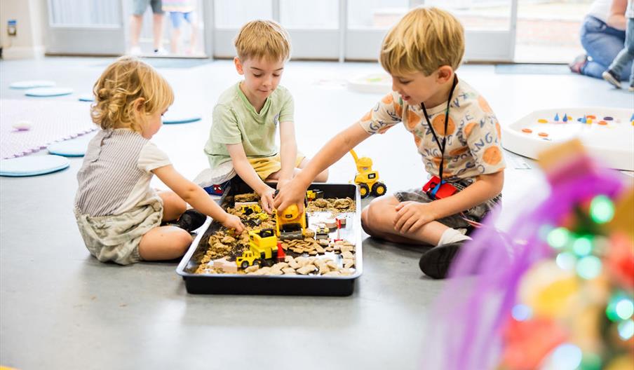 3 pre-school/toddler age children playing in a messy tray