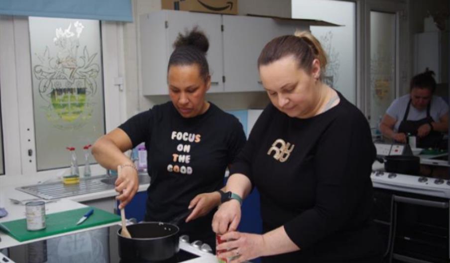 Two ladies participating in the programme cooking together and having fun