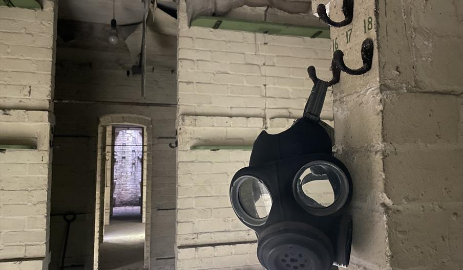 Image of men's sleeping quarters with gas mask in foreground