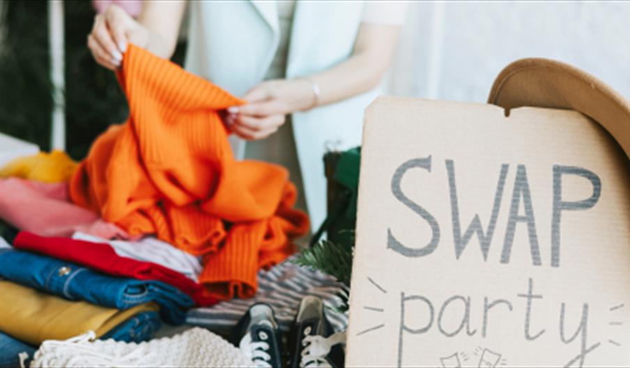 Clothes with a sign saying 'Swap Party'